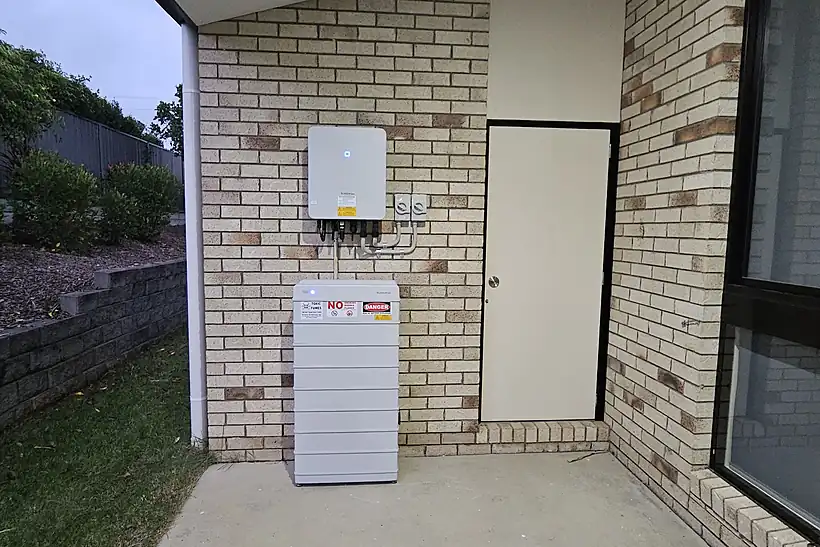 Inverter mounted above a stacked battery unit on the brick wall of a Queensland home