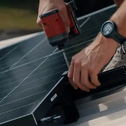 An installer fastening a solar panel clamp with a cordless driver on a corrugated roof