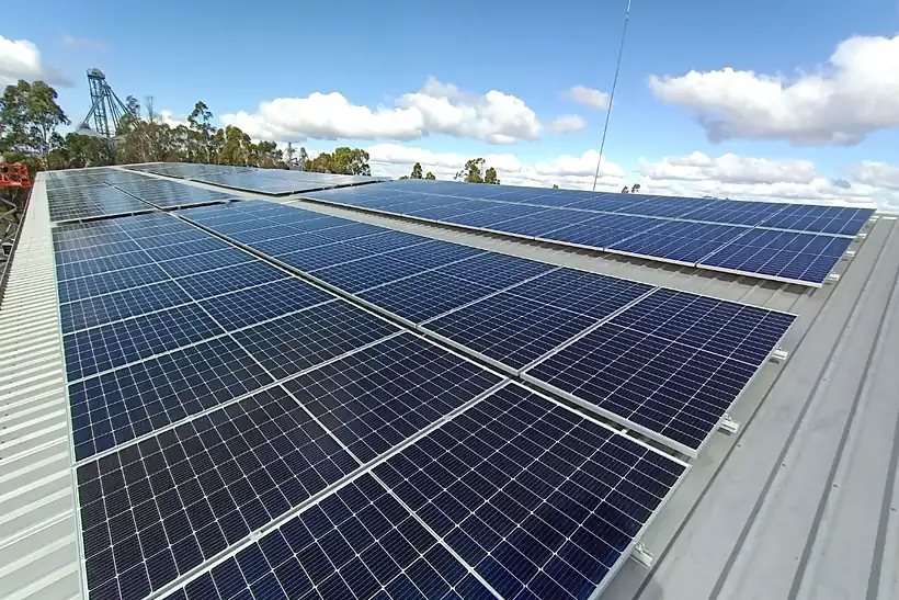 Solar panels on a corrugated shed roof in Dalby under a clear blue sky