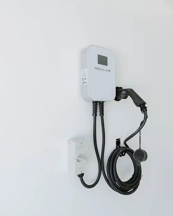 A new Ocular EV charger mounted on a white wall with its cable coiled