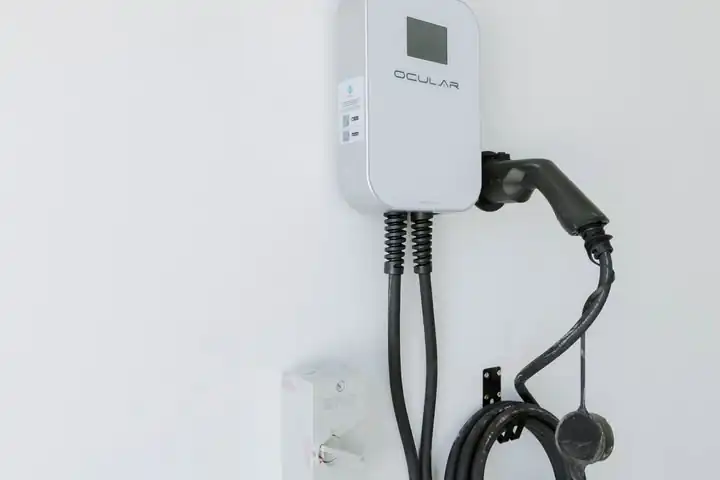 A new Ocular EV charger mounted on a white wall with its cable coiled
