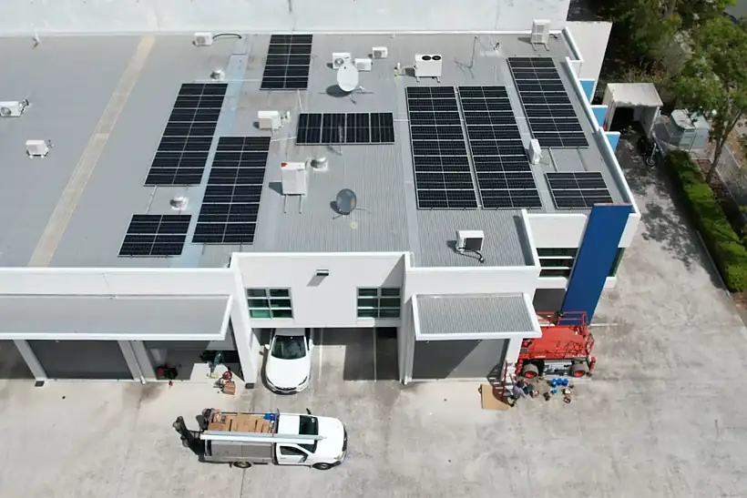 Aerial view of a flat commercial roof at Arundel with a 26.5 kW solar array and an LMS ute below