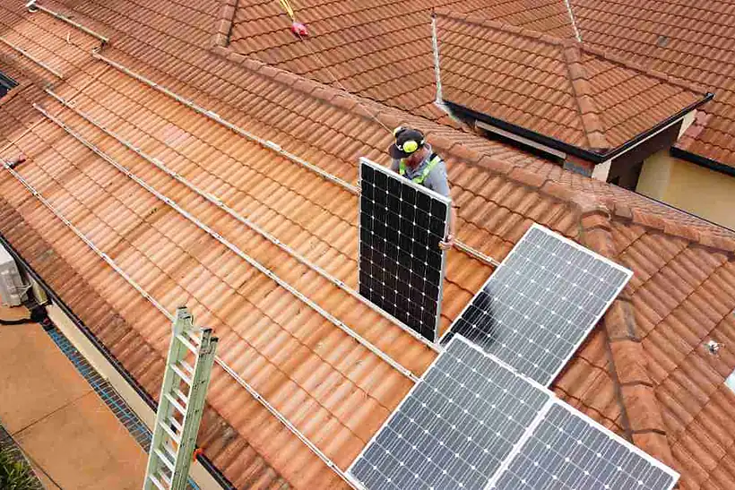 Aerial view of a terracotta roof with an installer lifting a panel off its rails before a roof restoration