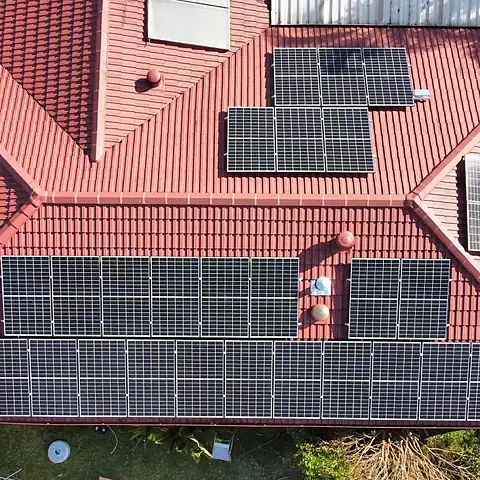 Aerial view of a red tiled house roof in South East Queensland with several rows of black solar panels installed by LMS Electrical