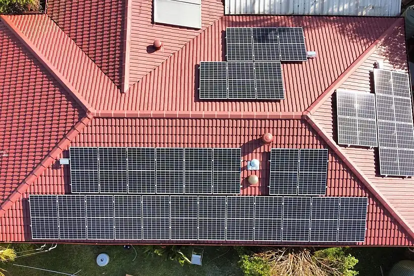 Aerial view of a red tiled house roof in South East Queensland with several rows of black solar panels installed by LMS Electrical