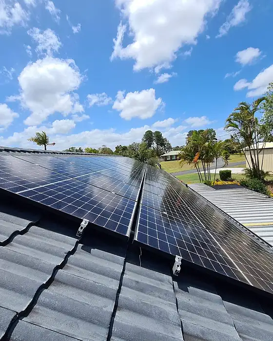 Close view of new solar panels on a concrete tile roof under a blue Queensland sky