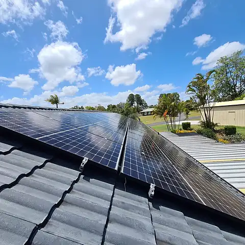 Close view of new solar panels on a concrete tile roof under a blue Queensland sky