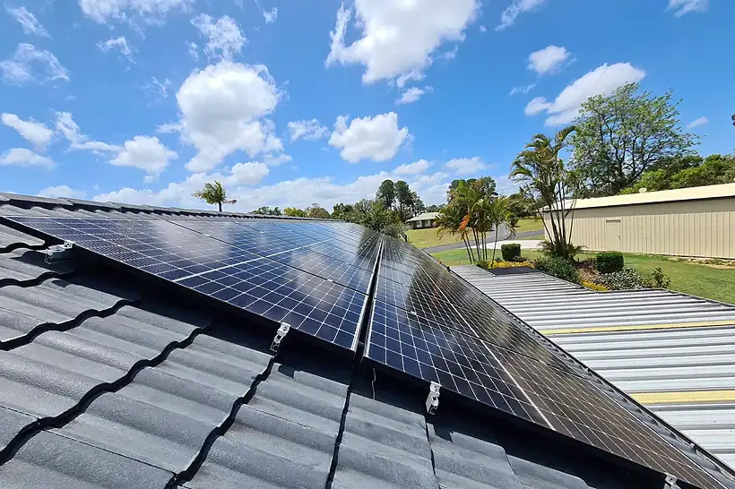Close view of new solar panels on a concrete tile roof under a blue Queensland sky