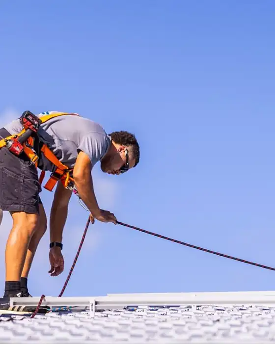 Two LMS Electrical installers in safety harnesses working on a metal roof