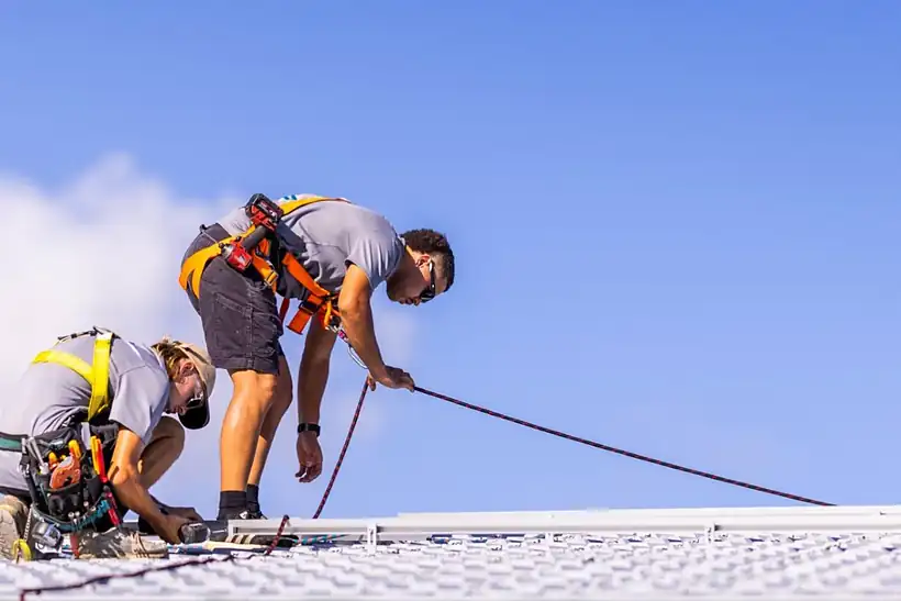 Two LMS Electrical installers in safety harnesses working on a metal roof